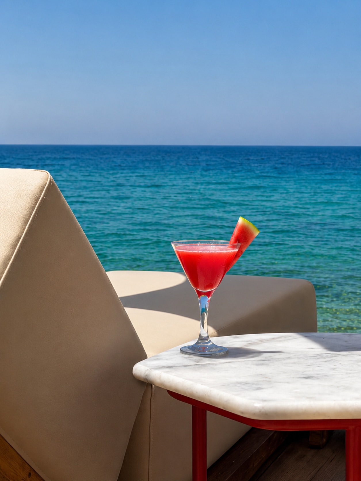 Watermelon cocktail on a marble table with the turquoise sea behind