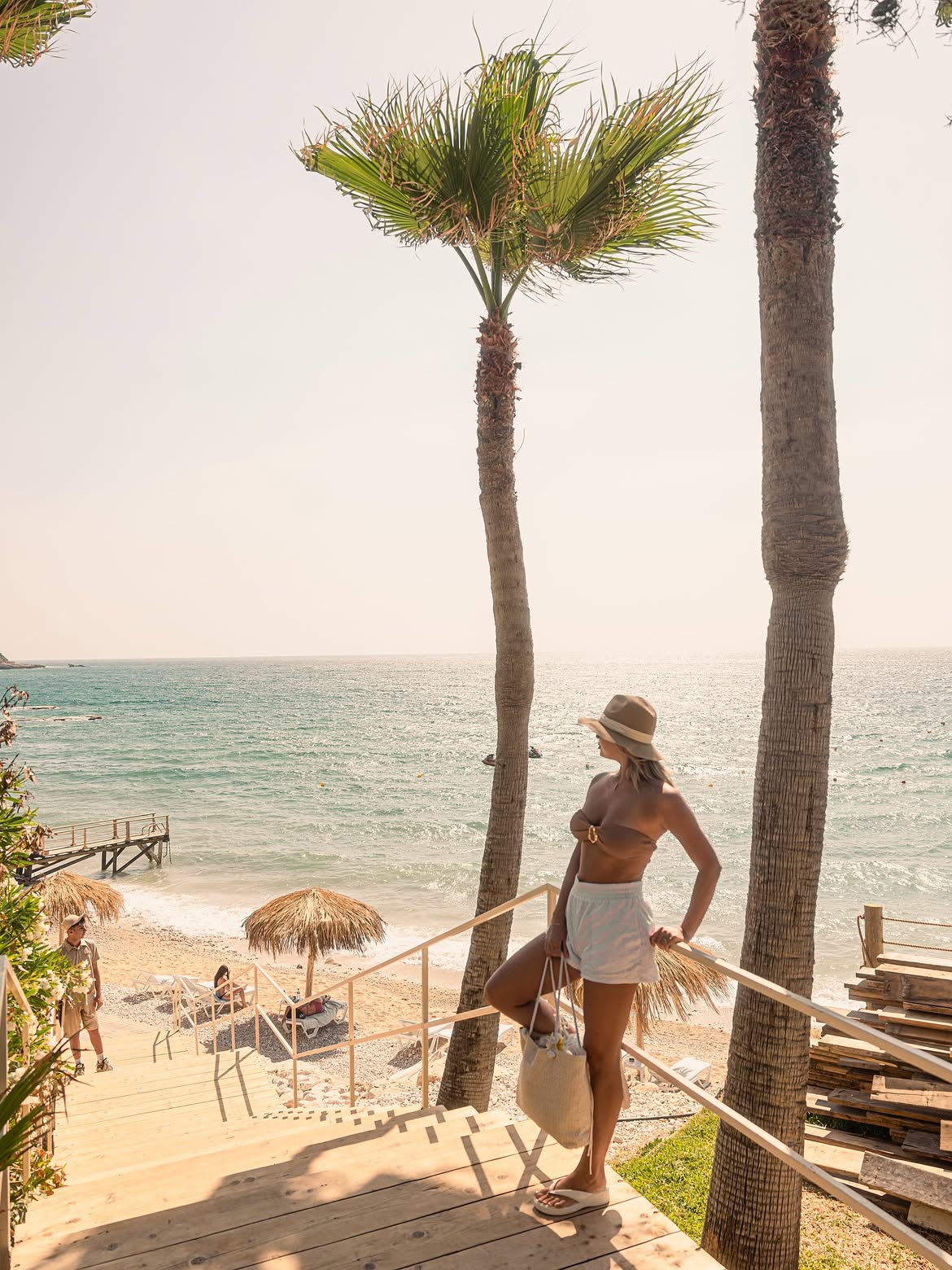 Guest walking down the timber steps to the beach between two palms
