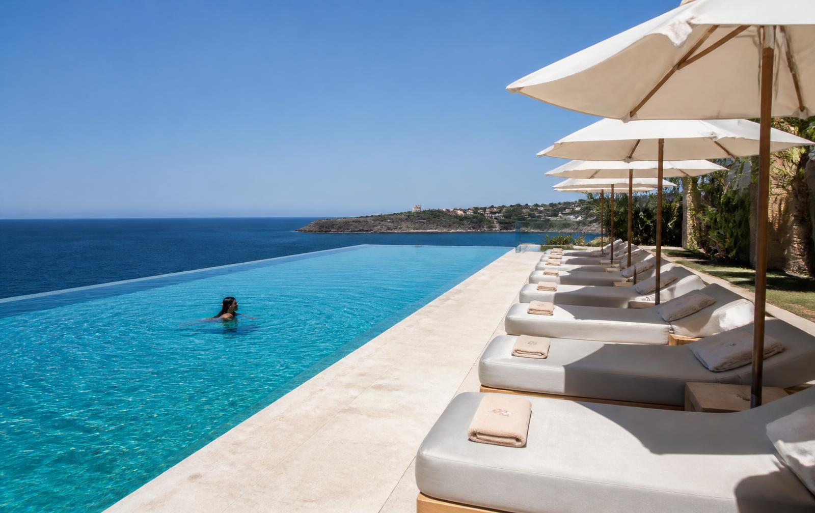 Long turquoise pool with loungers above the sea at Kai
